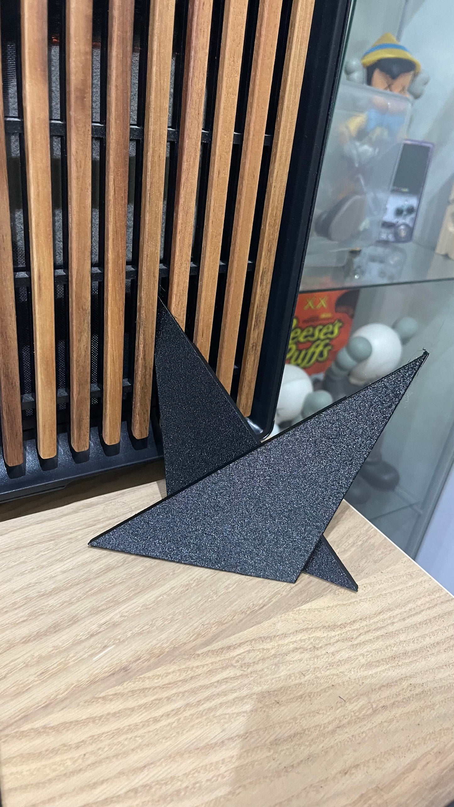 Two textured black triangles rest on a wooden surface. 
